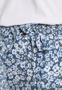 Blommönstrad kjol i nyanser av blått med knytning i midjan. Lätt material med små vita och blå blommor på en mörk bakgrund.