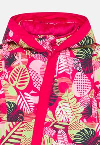 Ένα πολύχρωμο αδιάβροχο με ροζ βάση και σχέδια φύλλων σε πράσινο, μαύρο και άσπρο. Διαθέτει κουκούλα και μπροστινό φερμουάρ.