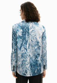 Blazer a fantasia blu e bianco con vestibilità sartoriale, maniche lunghe, spacco posteriore singolo e polsini con bottoni, caratterizzato da un design astratto.