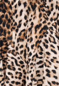 Material cu model de leopard în nuanțe de maro, bej și negru, având o cusătură centrală și pliuri în material.