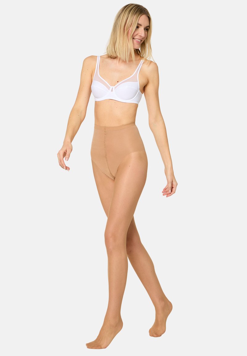 Letvægtige, nøgenfarvede strømpebukser med høj talje kombineret med en hvid bh med gennemsigtige stropper, der fremhæver et glat, sømløst design.