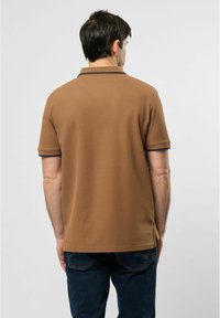 Hnědý polo shirt s texturovaným povrchem, kontrastním námořnickým límcem a akcenty na rukávech, a volným střihem, z pohledu zezadu.