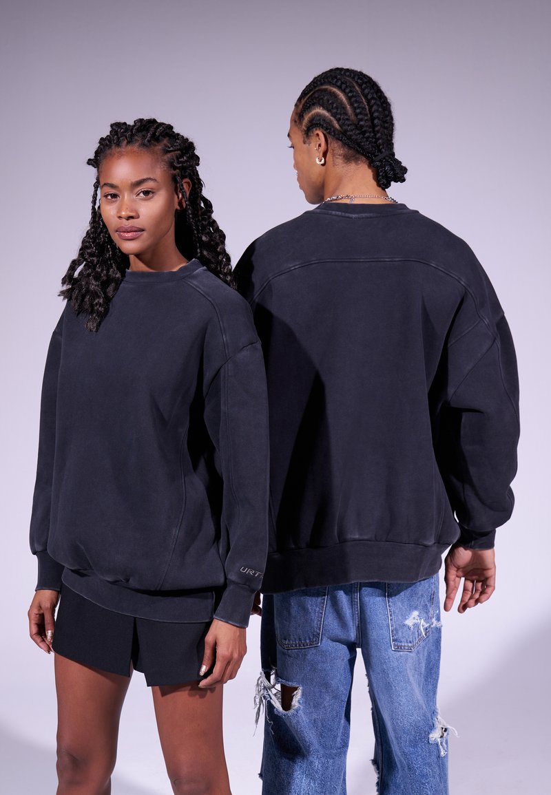 Sudadera negra de gran tamaño con cuello redondo, puños y dobladillo acanalados. Fabricada con material suave y con un ajuste relajado.