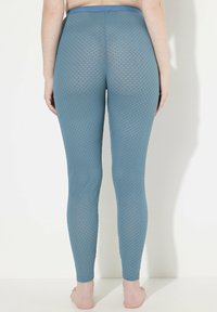 Leggings a rete blu con un motivo di pesce, dotati di un ampio elastico in vita e una silhouette aderente.