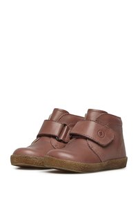 Stivali alla caviglia in pelle marrone con cinturino in velcro, design curvo, suola in gomma testurizzata e dettagli di cucitura rinforzati.