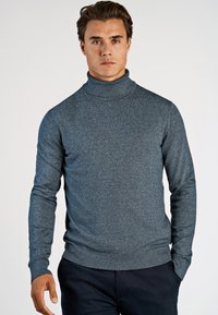 Ciemnoniebieski sweter w golfie o teksturowanym splotzie, z długimi rękawami, dopasowanym kroju oraz ściągaczami przy rękawach i u dołu.