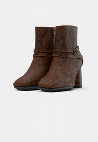 Botines de imitación de serpiente marrones con punta afilada, tacón cuadrado y una correa decorativa con hebilla plateada.