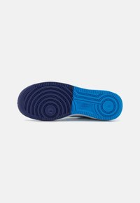 Semelle d'une sneaker avec des motifs circulaires texturés en bleu foncé et bleu vif, montrant le logo Nike près du centre.