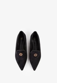 Scarpe nere con punta affusolata in tessuto texturizzato, dotate di un accento decorativo in tonalità oro sulla tomaia e di una fodera interna liscia.