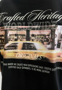 Sort t-shirt med grafisk print af en gul taxa og bysceneri, med hvid tekstoverlay og en falmet, vintage æstetik.