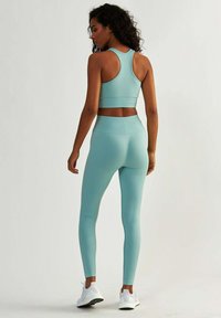 Bezszwowy zestaw odzieży sportowej w jasnoniebieskim kolorze, składający się z biustonosza sportowego z plecami w kształcie litery Y oraz legginsów o wysokim stanie, obydwa z subtelnym wzorem teksturowanym.