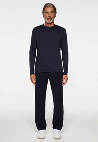 Mörkblå långärmad tröja kombinerad med svarta byxor. Mjukt tyg, avslappnad passform, rund halslinning och vita sneakers fulländar stilen.