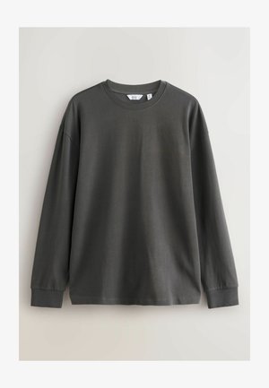 Donkergrijze langemouwen t-shirt met een ronde hals, gemaakt van zacht katoenmateriaal. Heeft een losse pasvorm en ribgebreide manchetten.
