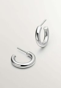 Pendientes de aro de plata con forma circular, que presentan una superficie lisa y brillante, así como un mecanismo de cierre seguro para su uso.
