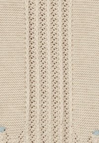 Tessuto lavorato a maglia beige chiaro con un motivo testurizzato caratterizzato da punti in rilievo attorcigliati e sezioni lisce, accentuato da piccoli puntini blu.