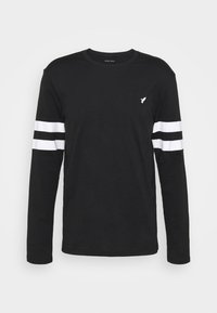 Svart långärmad T-shirt i bomullsmaterial, med tre vita ränder på båda ärmarna och en liten logotyp på bröstet. Klassisk rundhalssdesign.