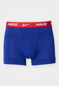 Blaue Boxershorts aus weichem Material, mit einem roten elastischen Bund und weißem "NIKE"-Branding. Das Design zeichnet sich durch eine enge Passform und kein Muster aus.