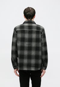 Μαύρο και γκρι καρό φανελένιο πουκάμισο με μακριά μανίκια, μανσέτες με κουμπιά και γιακά που διπλώνει, με ίσια γραμμή και ελαφριά υφή.