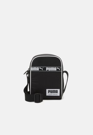 Petit sac bandoulière de sport noir Puma avec bordure blanche, fermeture éclair, sangle ajustable et logo Puma sur le panneau avant.