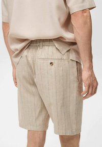 Beige gestreepte shorts van textuurstof, met een achterzak met een knop en een elastische tailleband voor comfort.
