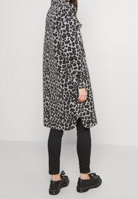 Leopardenmuster-Mantel in Grau und Schwarz, aus weichem Stoff. Verfügt über einen Kragen, Knopfverschlüsse und ein leicht länger geschnittenes Design mit abgerundetem Saum.