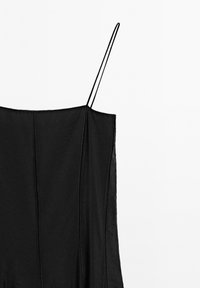 Sort udenærmet kjole med tynde stropper, der har en svævende silhuet og lodret sømdetaljering. Glat tekstur, minimalistisk design.