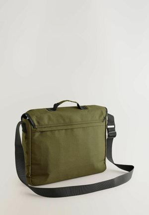 Zielona oliwkowa torba na ramię z górnym uchwytem, regulowanym czarnym paskiem oraz teksturowanym materiałem; ma zamek błyskawiczny i minimalistyczny design.