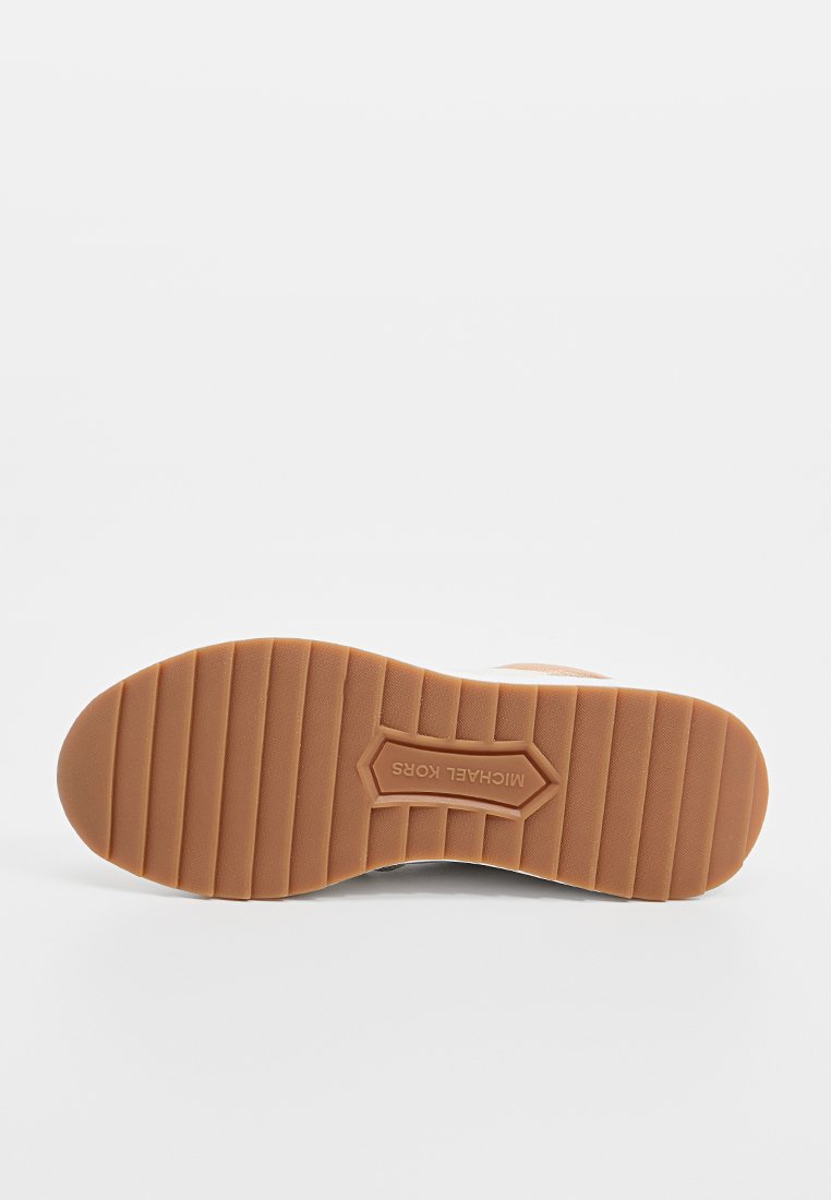 Semelle de sneaker en caoutchouc marron avec un motif texturé, présentant des rainures horizontales et un logo intégré dans une section blanche près du talon.