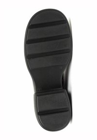 Suela de zapato de goma negra con superficie texturizada, que presenta ranuras horizontales y bordes redondeados para mayor agarre y flexibilidad.