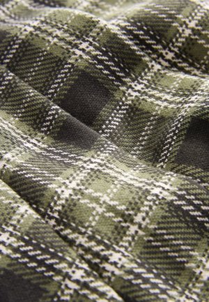 Zeleno-črno karo blago z mehkim občutkom, ki ima bele črte, ki ustvarjajo karo vzorec in rahlo sijaj.