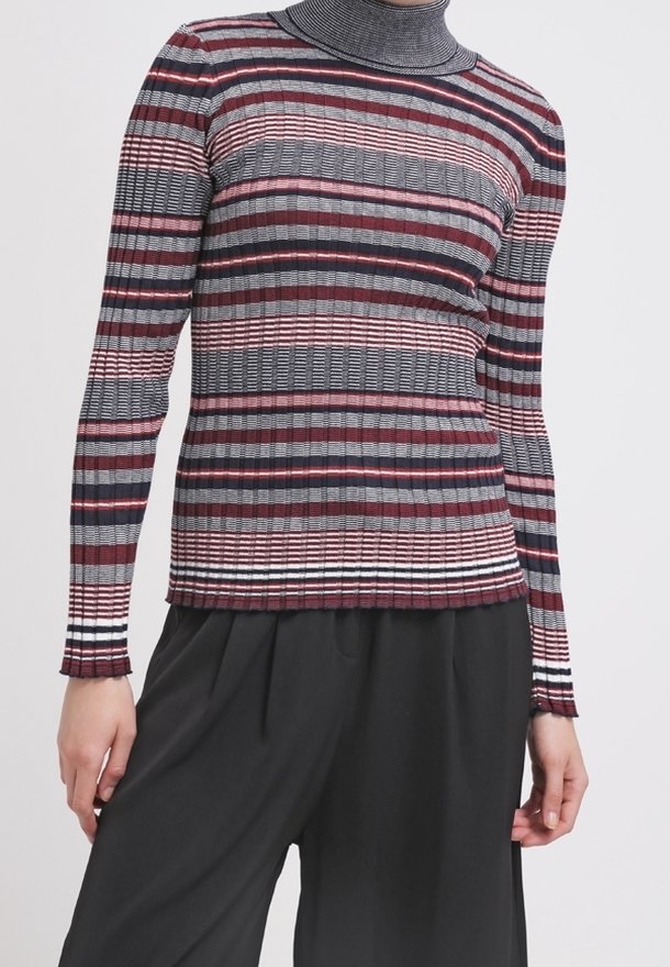 Svetr s dlouhým rukávem a vysokým límcem v proužkované šedé, vínové a černé barvě s žebrovanou texturou. Ozdoben tenkými bílými pruhy na spodním lemu.