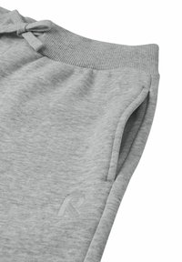 Light gray sweatpants made from soft fabric, featuring a ribbed waistband, side pockets, and a subtle embroidered logo on the leg.