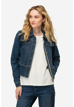 Denim jasje, donkerblauw, vervaagde afwerking, knoopsluiting aan de voorkant, puntige kraag, twee borstzakken, gecombineerd met een wit shirt en blauwe spijkerbroek.
