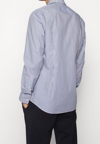 Gestreepte lange mouwen overhemd in marineblauw en wit, met een getailleerde pasvorm, knoopsluiting bij de manchetten en een ronde zoom. Soepele katoenstof.