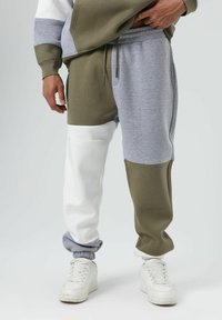 Sweatpants met kleurvlakken in olijfgroen, grijs en wit. Gemaakt van zachte, gestructureerde stof met elastische boorden en zakken. Voorzien van een verstelbare tailleband.