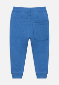 Kék pamut melegítőnadrág puha textúrával, rugalmas derékpánttal és egyetlen hátsó zsebbel. Egyszerű kialakítás, további minták vagy díszítések nélkül.