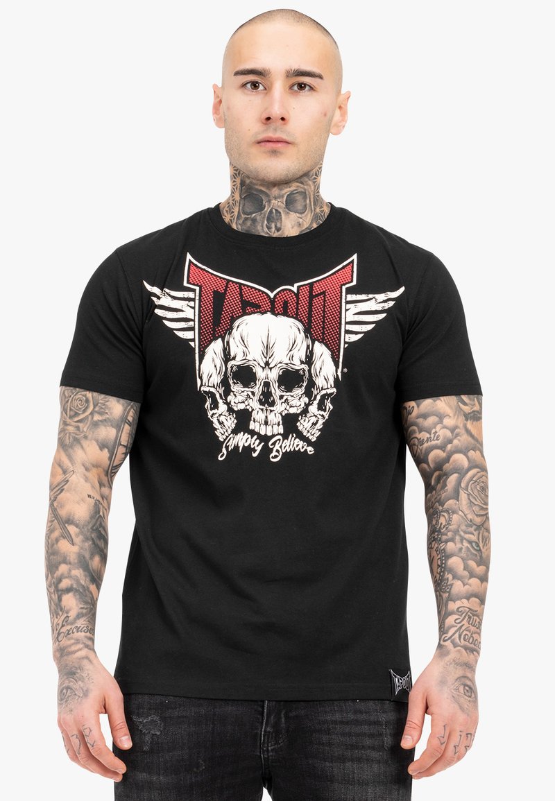 Schwarzes Baumwoll-T-Shirt mit einem großen Grafikdruck eines Schädels mit Flügeln und dem Wort "TAPOUT" in Rot, mit weißen Akzenten und abgenutzten Details.