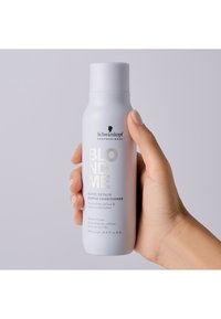 Vit flaska med ett grått lock, prydd med svart och metalliskt silvertext. Etiketten lyder "BLONDME Bond Repair Purple Conditioner," 250 ml.