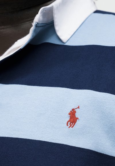 Kék csíkos rögbi ing fehér gallérral, mellrészen kis piros hímzett pólójátékos logóval.