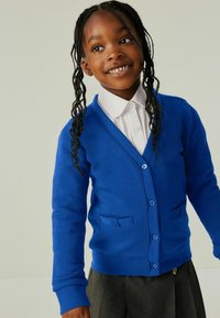 Plavi kardigan od mekog materijala, s V izrezom, dugim rukavima i dva prednja džepa. Završava s gumbima i glatkom teksturom.