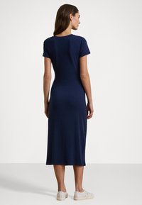 Abito midi fitted blu navy a maniche corte con scollatura rotonda; texture morbida e orlo sopra il ginocchio, abbinato a sneakers chiare.