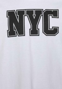 Vit T-shirt med fet svart tryck av "NYC" i blockbokstäver med kontur. Mjukt material med en slät textur.