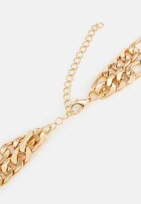 Guld kædethalskæde med store led og en tekstureret overflade, udstyret med en lukning med krog og en justerbar forlængerkæde.
