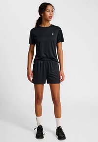 Svart sportoutfit bestående av en åtsittande kortärmad tröja och matchande shorts, tillverkade av ett slätt, lätt tyg.