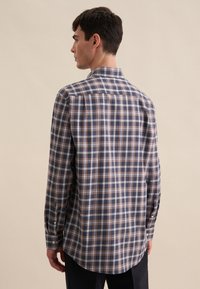 Camicia a maniche lunghe con bottoni in tartan navy, marrone e bianco; presenta un colletto classico e un orlo arrotondato con polsini a un bottone.