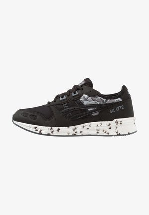 Baskets Asics Gel Lyte noires avec des détails à motifs noirs et blancs et une semelle blanche tachetée.