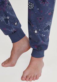 Marineblauwe sweatpants met een kosmisch ontwerp van sterren en planeten, elastische boorden bij de enkels, zachte stofstructuur.