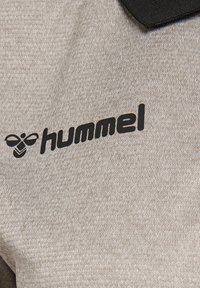 Grijze, gestructureerde stof met een fijne afwerking. Bevat een zwart "hummel" logo met een bijontwerp. Eenvoudig ontwerp zonder extra details.