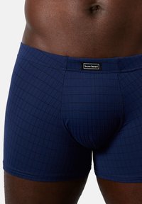 Marineblå boxer shorts lavet af strækbart stof med et gittermønster. Har en mærket talje og en tætsiddende pasform for komfort.