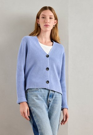 Light blue ribbed cardigan with a V-neck, three large buttons, long sleeves, and a relaxed fit, paired with light blue jeans.